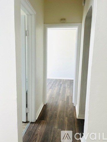 A hallway with wood flooring and white walls.
