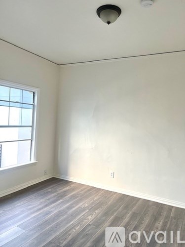 A room with a window and wooden flooring.