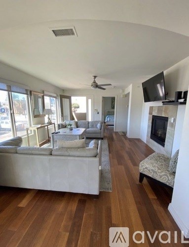 A living room with a white couch and a television mounted on the wall.