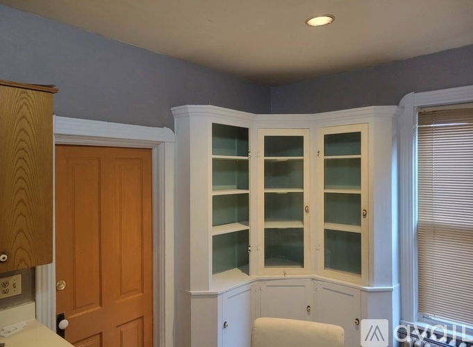 A kitchen with a wooden door and a white cabinet with glass doors.