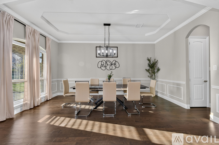 A dining room with a table set for six and a chandelier hanging from the ceiling.