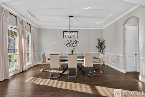 A dining room with a table set for six and a chandelier hanging from the ceiling.