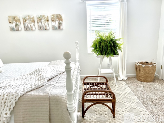 A white bedroom with a white bed and a white chair.