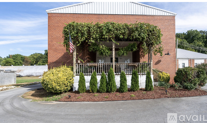 A red brick building with a flag on top and a white fence in front.