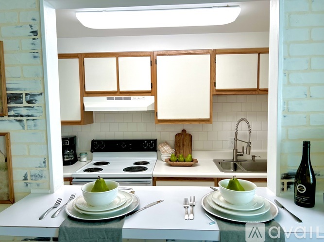 A kitchen with a white countertop and a stove with a pot on it.
