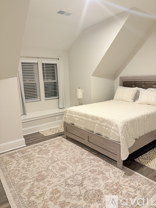 A bedroom with a large bed and a rug on the floor.