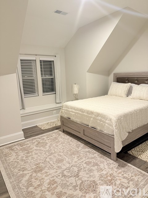 A bedroom with a large bed and a rug on the floor.