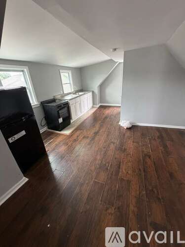 A room with wooden flooring and a black object on the left side.
