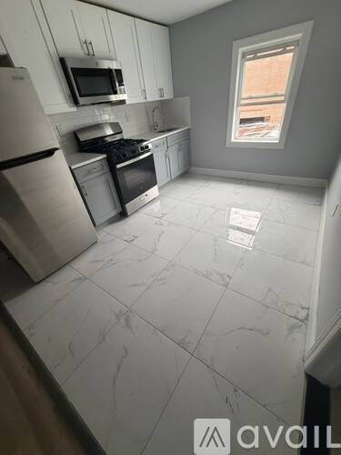 A kitchen with white cabinets and a window.