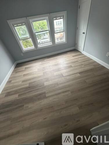 A room with wooden flooring and a window with a view of trees.