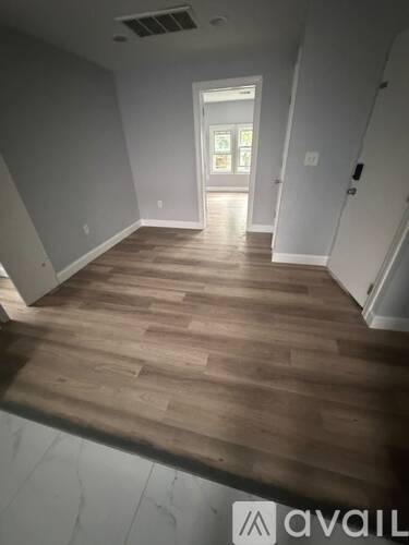 A room with wooden flooring and a doorway leading to another room.