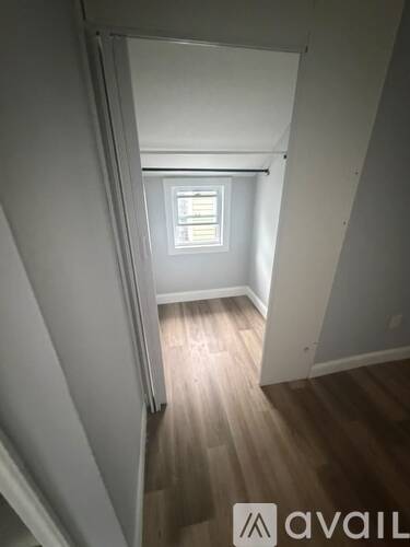 A room with a window and wooden flooring.