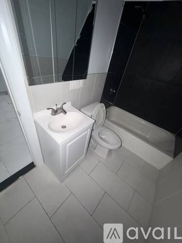 A white toilet with a bidet attachment is in a bathroom with black tiles.