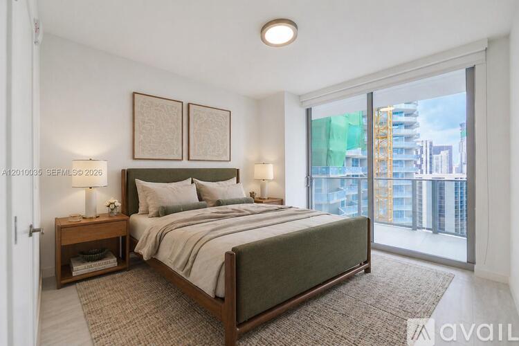 A bedroom with a large bed and a view of a building outside the window.