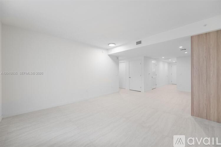 A spacious room with white walls and a wooden door.