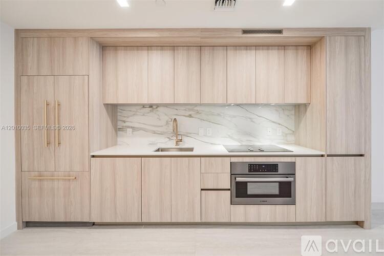 A modern kitchen with wooden cabinets and a marble countertop.