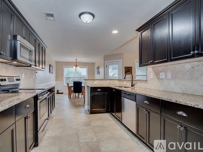 A kitchen with black cabinets and a marble countertop.