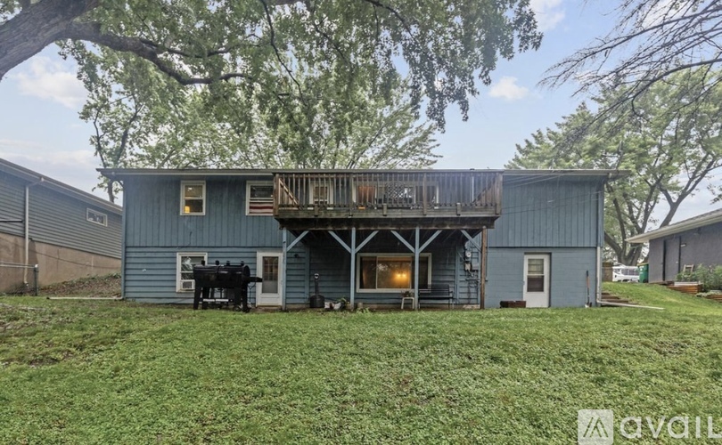 A blue house with a porch and a tree in front.