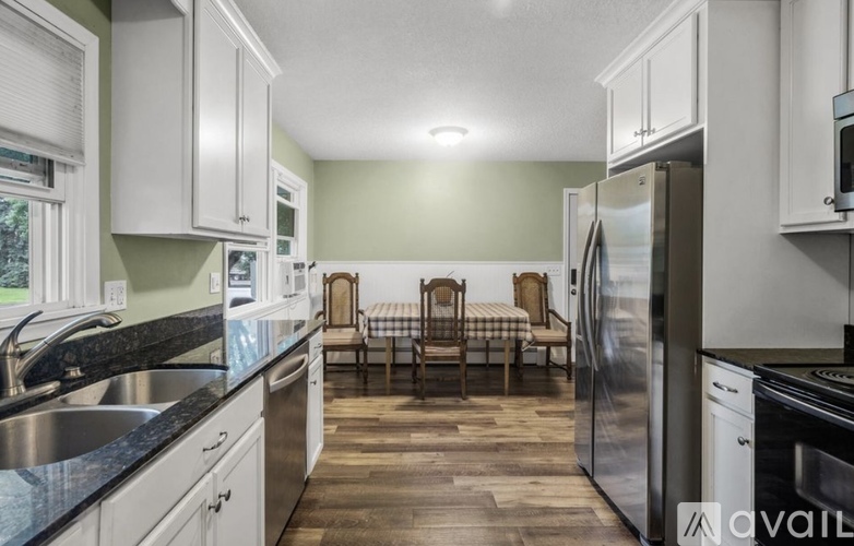 A kitchen with a stainless steel refrigerator and wooden flooring.