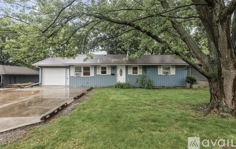 A house with a blue exterior and a large tree in front.