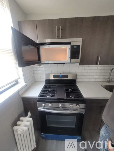 A kitchen with a black stove top oven and a black microwave above it.