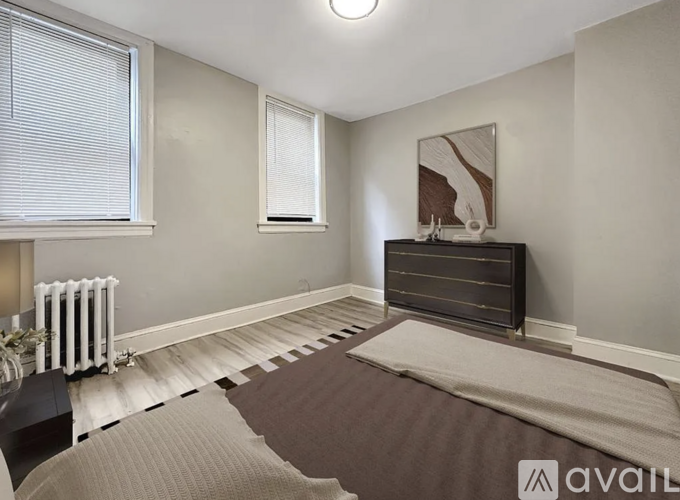 A bedroom with a bed, a radiator, and a painting on the wall.
