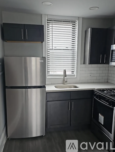 A kitchen with a stainless steel refrigerator and black cabinets.