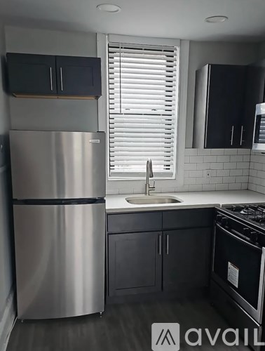 A kitchen with a stainless steel refrigerator and black cabinets.