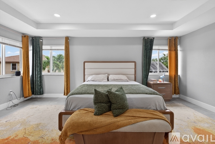A bedroom with a large bed and a window with curtains.