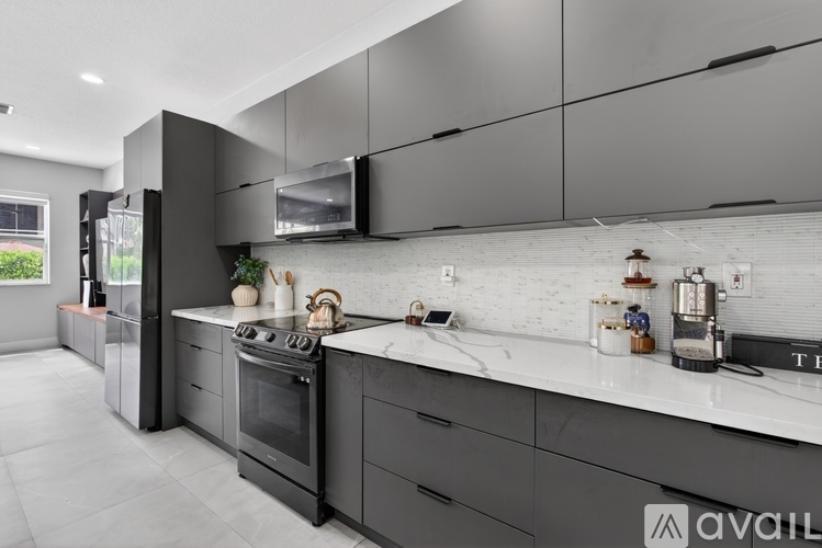 A modern kitchen with dark grey cabinets and a white countertop.