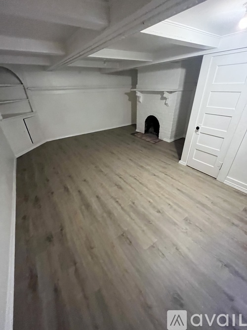 A room with a fireplace and wooden flooring.