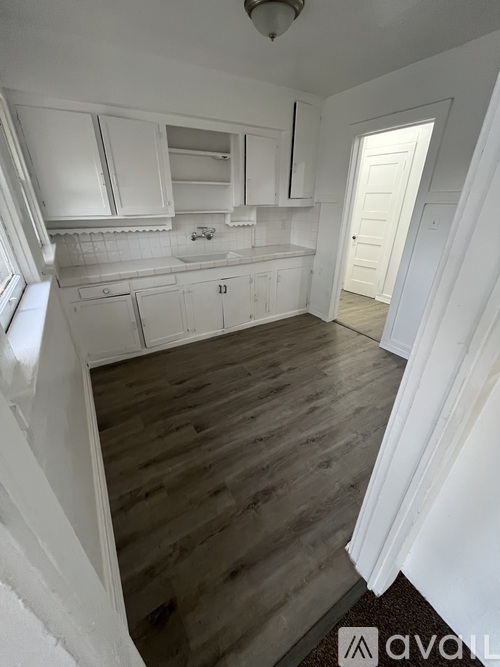 A kitchen with white cabinets and a wooden floor.