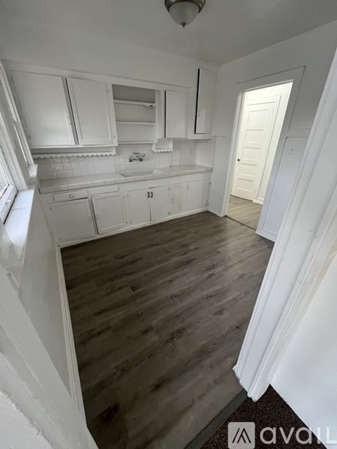 A kitchen with white cabinets and a wooden floor.