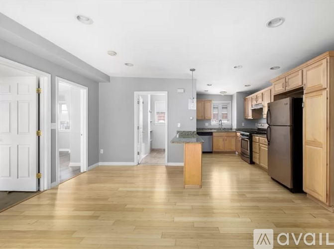 A kitchen with wooden floors and cabinets, and a dining area with a table and chairs.