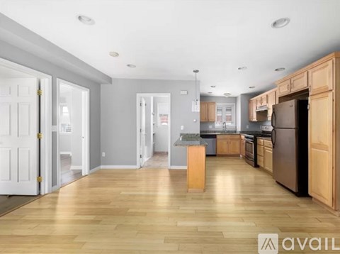 A kitchen with wooden floors and cabinets, and a dining area with a table and chairs.