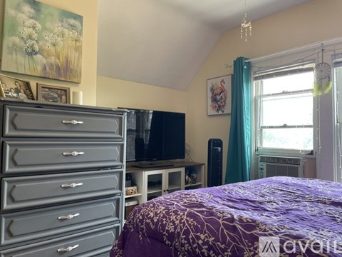 A bedroom with a purple bedspread and a TV on a stand.