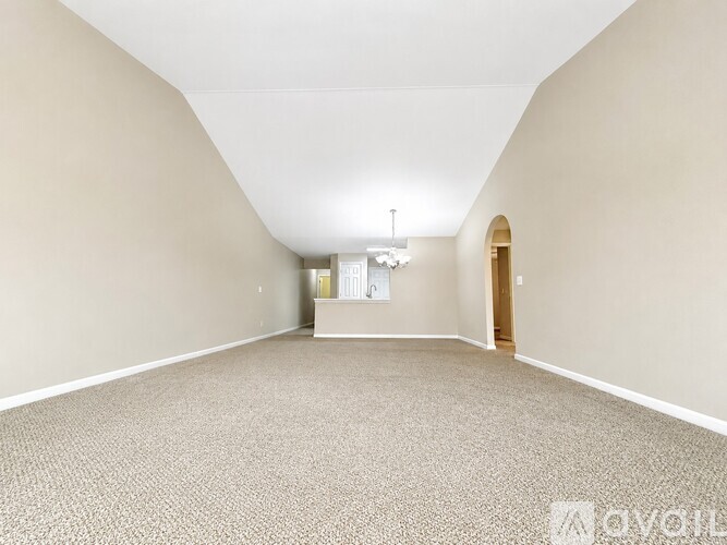 A spacious room with a carpeted floor and a door on the right side.