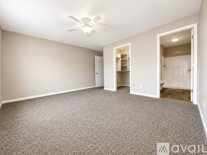 A room with a ceiling fan and carpeted floor.