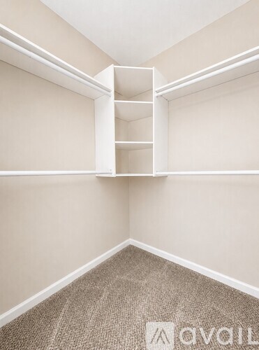 A room with a carpeted floor and a white shelf.