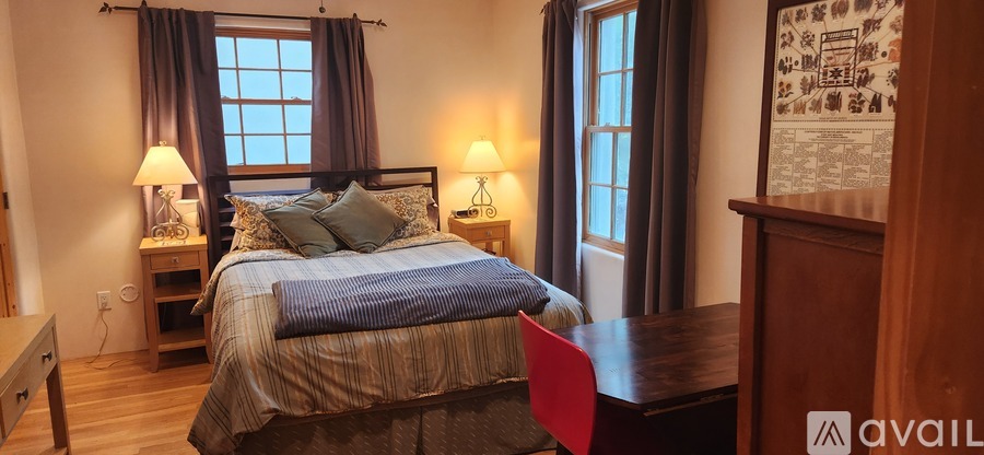 A bedroom with a large bed and a red chair.