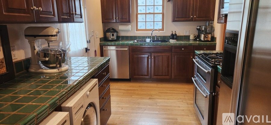 A kitchen with wooden cabinets and a green tile backsplash.