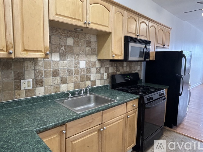 A kitchen with wooden cabinets and a black refrigerator.