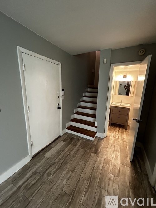 A room with a white door and a staircase leading to a second floor.