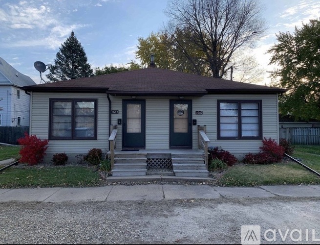 A house with a blue door and a brown roof is for sale.