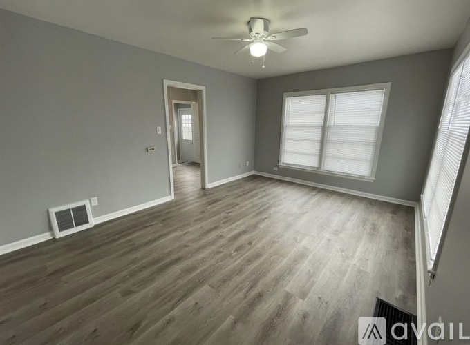 A spacious room with wooden flooring and a ceiling fan.