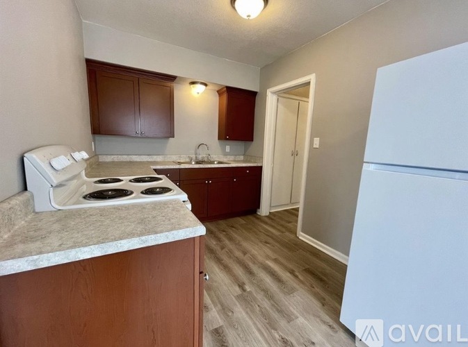 A kitchen with a white stove top oven and wooden cabinets.