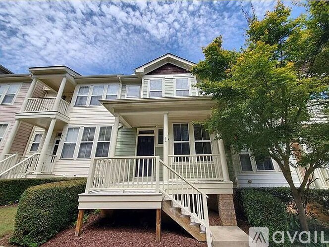 A two-story house with a balcony and a tree in front.