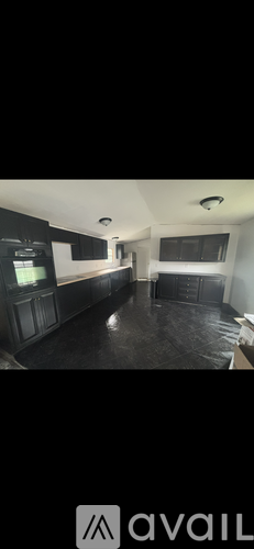 A spacious room with dark flooring and a large window.