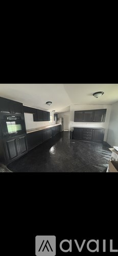 A spacious room with dark flooring and a large window.