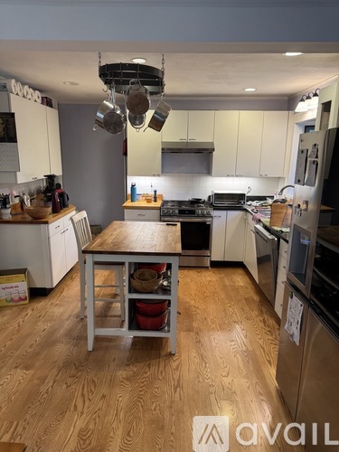 A kitchen with wooden floors and a table in the middle.